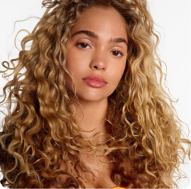 Woman with curly blonde hair on a plain background