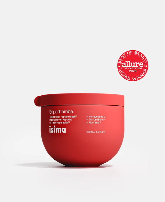 A round, red jar of Isima Súperbomba Triple Repair Peptide Mask with white lettering and a small side handle showcases its patent-pending advanced hair repair formula, positioned beside a red Allure Best of Beauty Award Winner 2023 seal.