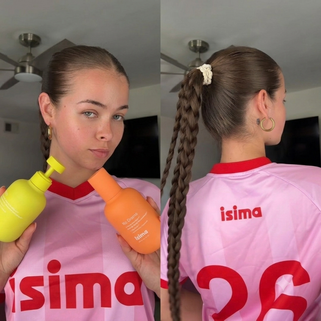 A woman with a long braided ponytail wears the isima Limited Edition Fútbol Jersey. Facing forward, she holds two colorful bottles and looks at the camera; from behind, the jersey’s name and number 26 stand out—a true match-day essential.