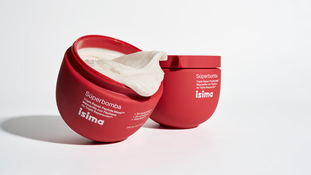 Two red jars of isima's Shakira's Curl Love Ritual ($138 Value) sit on a white background—one open, overflowing with creamy product for waves and curls, the other closed. Both feature visible product labels on the front.
