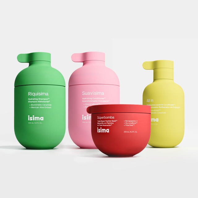 Four colorful isima hair care products from Shakira's Wash Day Ritual—green, pink, and yellow bottles alongside a red tub—are arranged on a white background. Each container features a pump or lid and the product name printed on the front. Specially formulated for waves and curls, they nourish and care for textured hair.